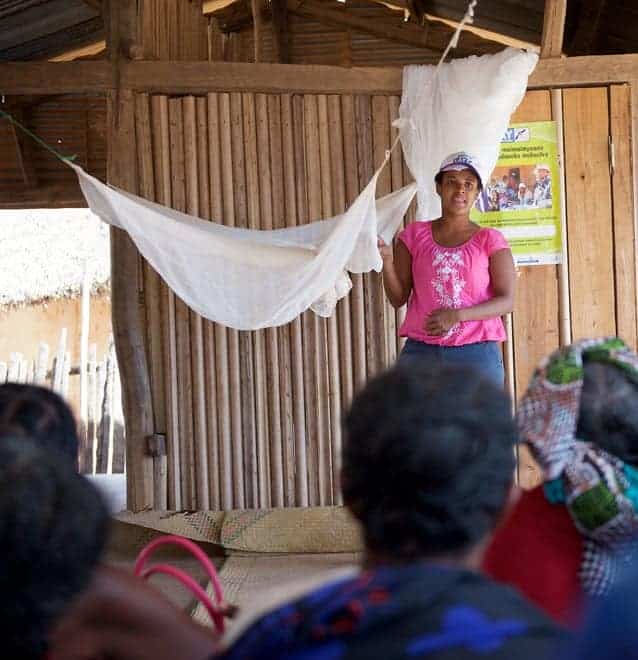 Photo of a woman giving a lecture about malaria nets